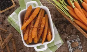 Carottes rôties dans un plat blanc, entourées d'épices : cannelle, genièvre, noix de muscade.